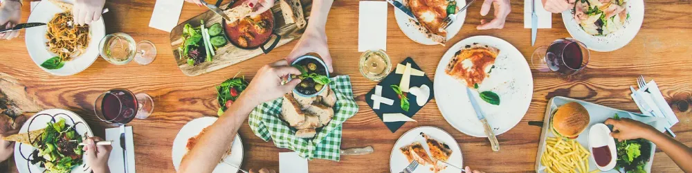 Family or friends summer party or outdoor dinner. Flat-lay of group of people at big table in cafe eating verious food together. Summer gathering or celebration concept